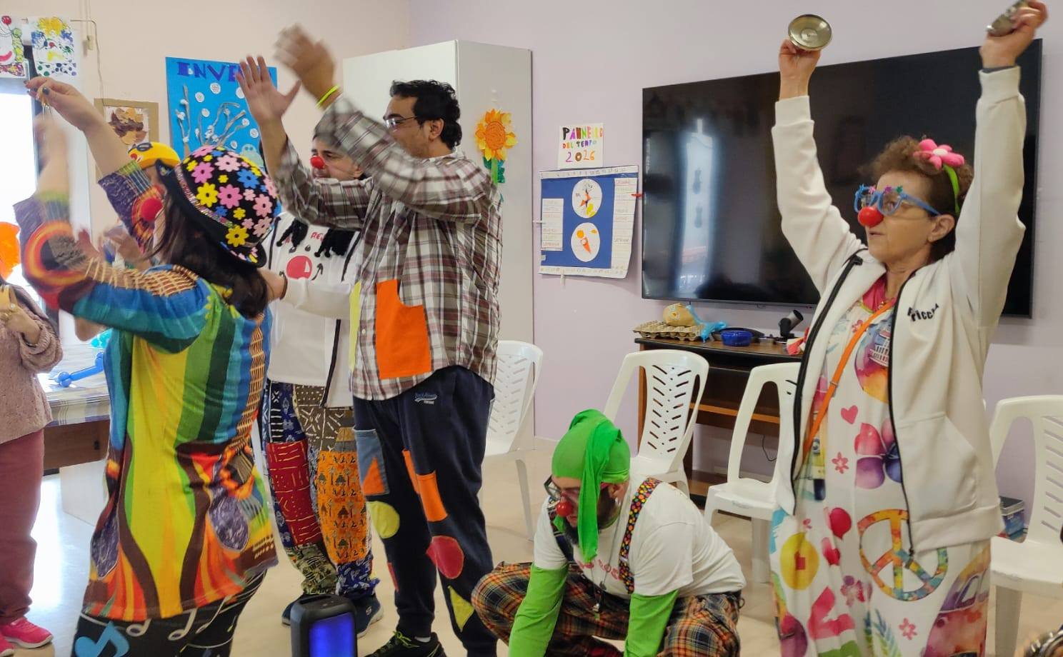 Clown e partecipanti con le braccia alzate durante una festa in una struttura